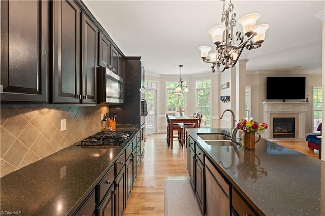 kitchen with stainless steel microwave, a sink, a chandelier, light wood-style floors, and ornamental molding