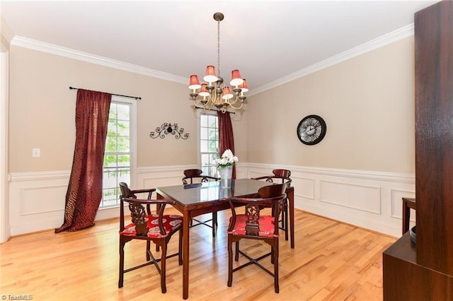 dining room with a chandelier, crown molding, light wood-type flooring, and wainscoting