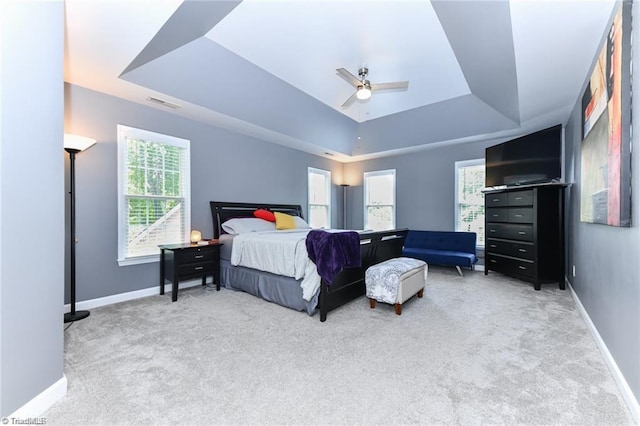 bedroom featuring a tray ceiling, carpet, baseboards, and ceiling fan