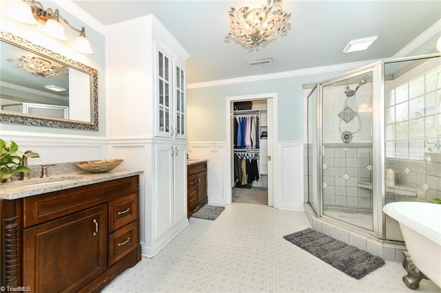 bathroom with a shower stall, vanity, ornamental molding, a soaking tub, and a wainscoted wall