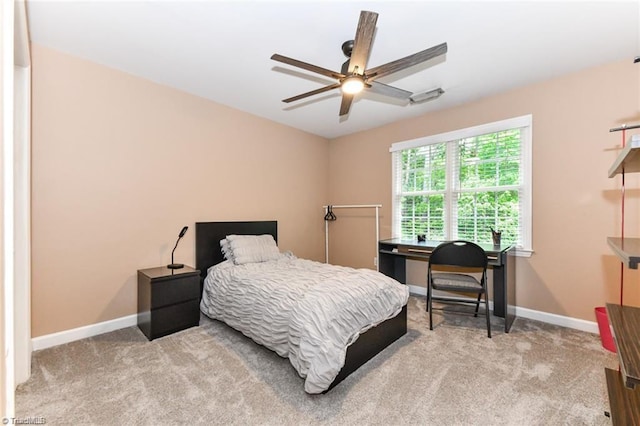 bedroom featuring light carpet, baseboards, a ceiling fan, and an office area