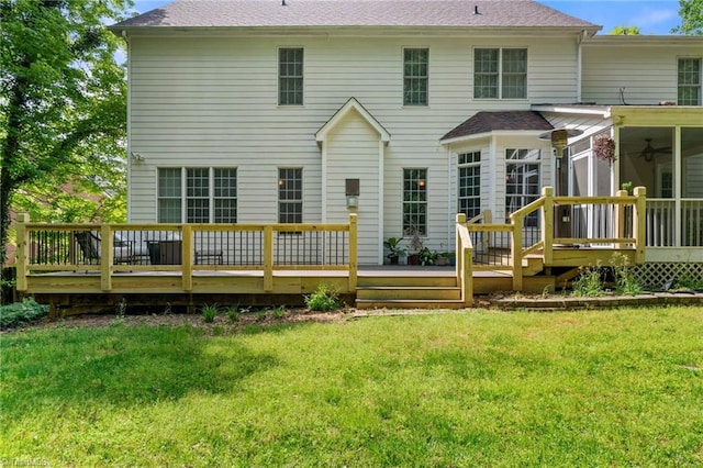 rear view of property featuring a wooden deck, a lawn, a shingled roof, and a sunroom