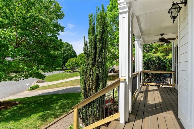 wooden terrace featuring a porch, ceiling fan, and a yard