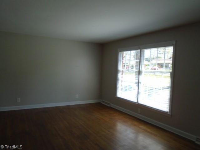 unfurnished room with a healthy amount of sunlight and dark wood-type flooring