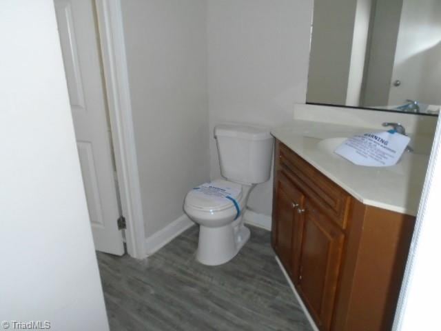 bathroom with wood-type flooring, toilet, and vanity