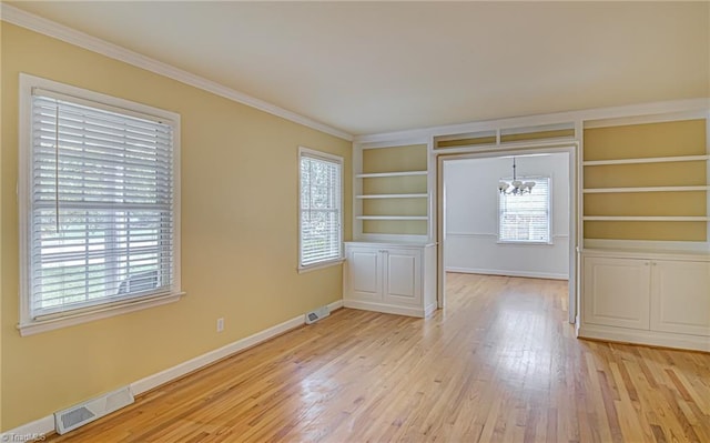 entrance foyer with ornamental molding, a wealth of natural light, light hardwood / wood-style flooring, and a chandelier