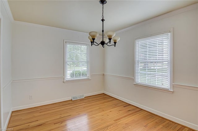 empty room with crown molding, a notable chandelier, and hardwood / wood-style floors