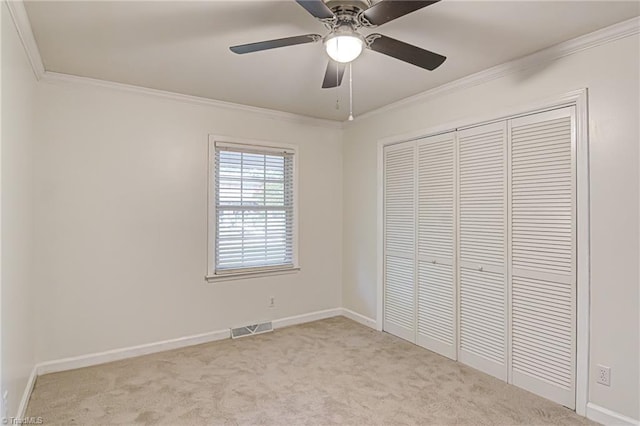 unfurnished bedroom with light carpet, crown molding, ceiling fan, and a closet