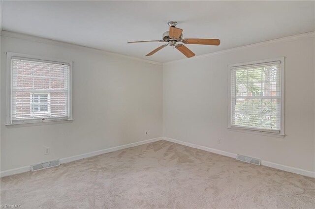 spare room with light colored carpet, ceiling fan, and ornamental molding