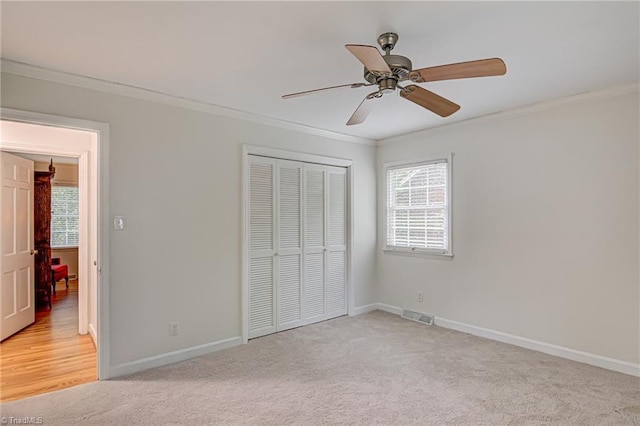 unfurnished bedroom with a closet, ceiling fan, light carpet, and ornamental molding