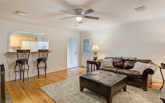 living room with crown molding, light hardwood / wood-style flooring, and ceiling fan