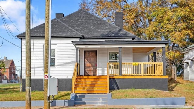 bungalow with a porch and a front lawn