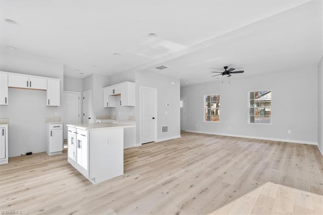 kitchen featuring white cabinets, ceiling fan, a kitchen island, and light wood-type flooring