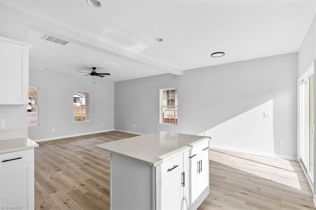 kitchen with ceiling fan, a kitchen island, light wood-type flooring, and white cabinetry