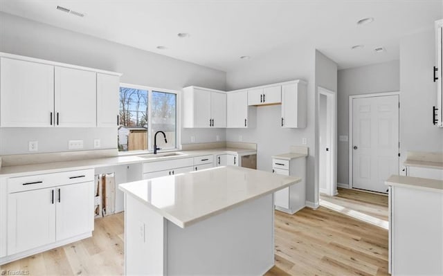 kitchen featuring sink, a center island, white cabinets, and light hardwood / wood-style flooring