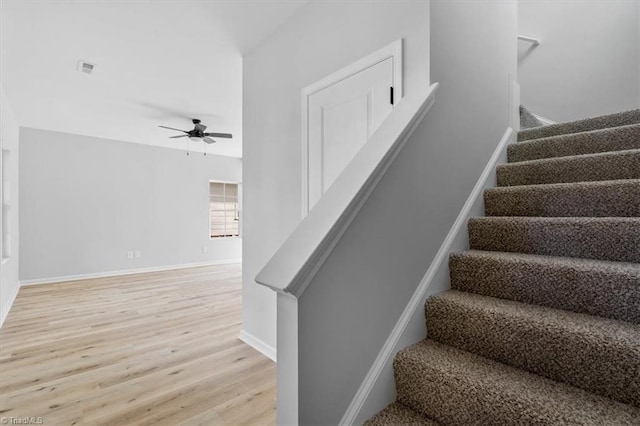 stairs featuring ceiling fan and hardwood / wood-style flooring