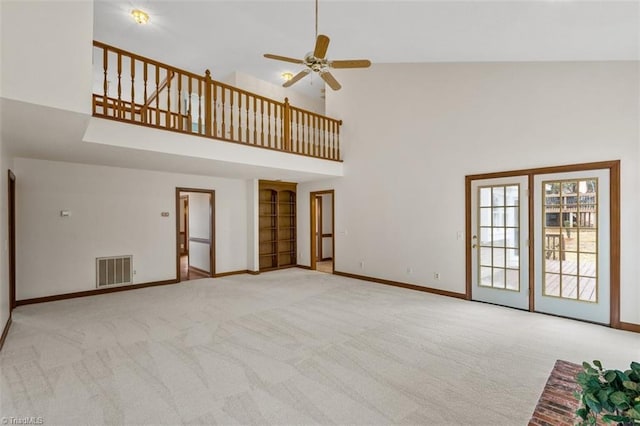 unfurnished living room with light colored carpet, visible vents, a towering ceiling, a ceiling fan, and baseboards