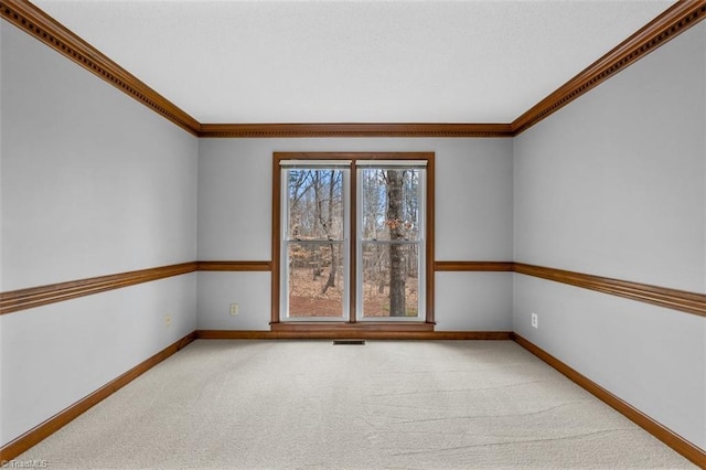 spare room featuring ornamental molding, carpet flooring, visible vents, and baseboards