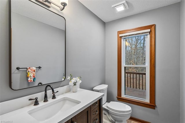 bathroom featuring a textured ceiling, vanity, and toilet