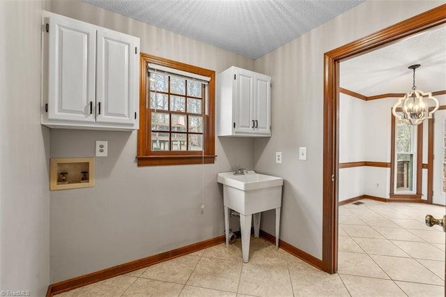 washroom featuring light tile patterned floors, a textured ceiling, hookup for a washing machine, and cabinet space