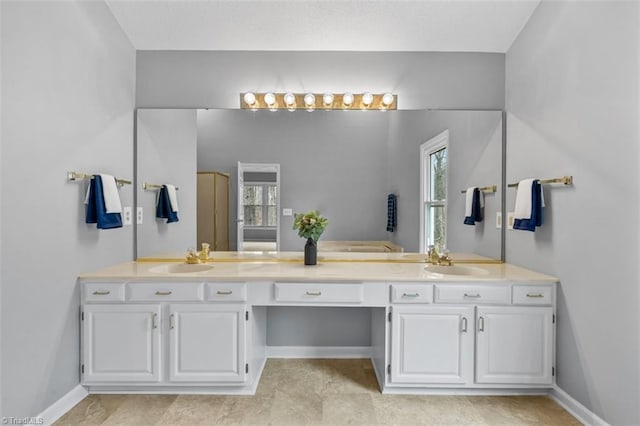 full bath with a sink, baseboards, and double vanity