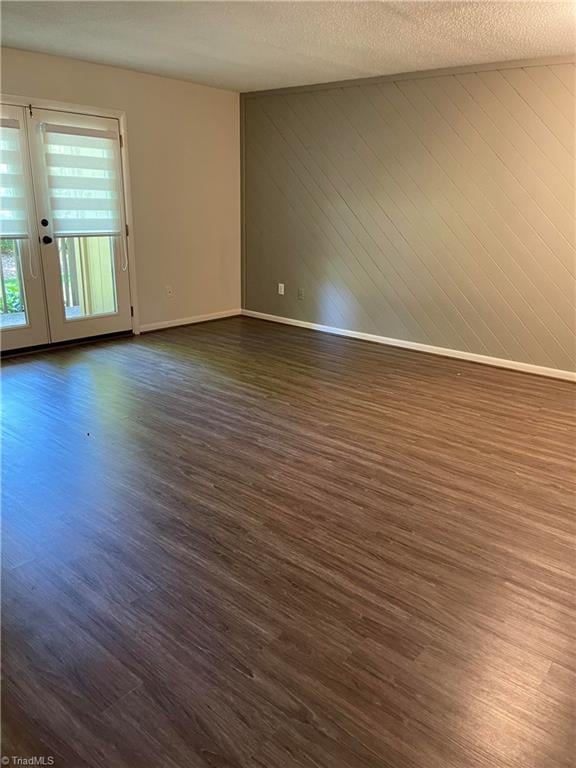 159 Turnwood Ln, Winston-Salem, NC 27104 - unfurnished room with french doors, dark wood finished floors, wooden walls, and a textured ceiling