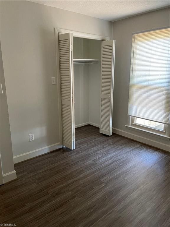 159 Turnwood Ln, Winston-Salem, NC 27104 - unfurnished bedroom with multiple windows, dark wood-style floors, a closet, and a textured ceiling