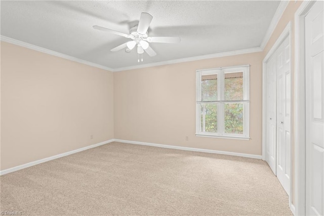 carpeted spare room featuring ceiling fan, a textured ceiling, and ornamental molding