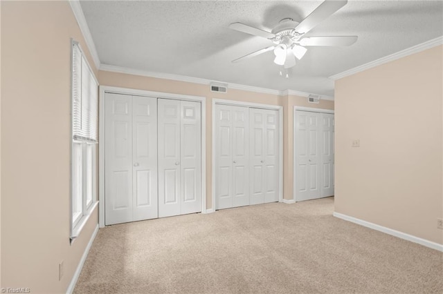 unfurnished bedroom with multiple closets, ceiling fan, and crown molding