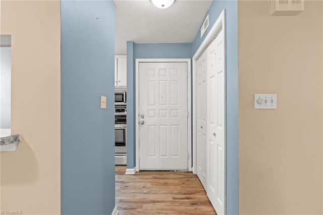 hall featuring a textured ceiling and light hardwood / wood-style flooring