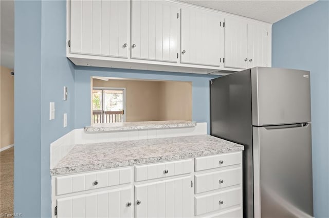 kitchen with white cabinetry, carpet, a textured ceiling, and stainless steel fridge