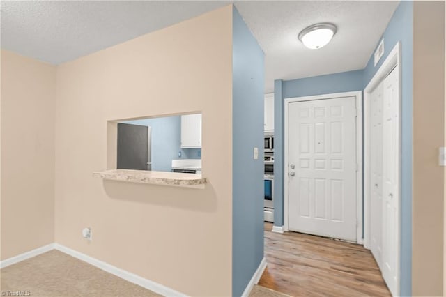 hallway with a textured ceiling and light wood-type flooring