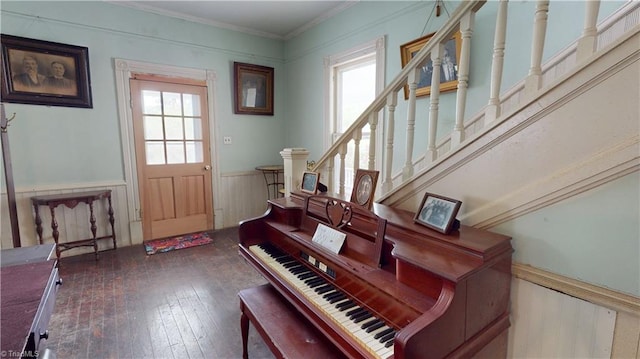 foyer entrance with a wainscoted wall, hardwood / wood-style flooring, ornamental molding, and stairway