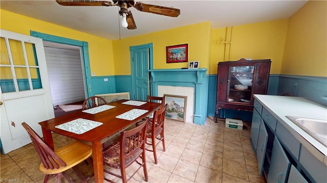 dining room with a wainscoted wall, a ceiling fan, and light tile patterned floors