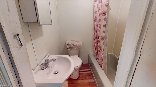bathroom featuring a sink, wood finished floors, toilet, and shower / tub combo with curtain