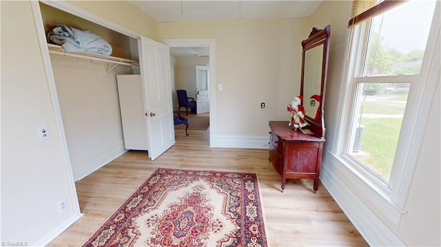 corridor with light wood finished floors, baseboards, and an office area