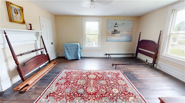 sitting room with wood finished floors, plenty of natural light, crown molding, and baseboards