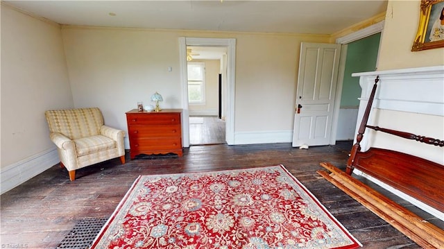 sitting room with wood-type flooring, crown molding, and baseboards