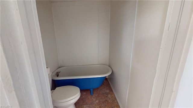 full bathroom with toilet, a tub, and baseboards