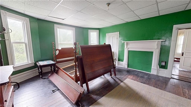 bedroom with hardwood / wood-style flooring, a drop ceiling, multiple windows, baseboards, and a fireplace