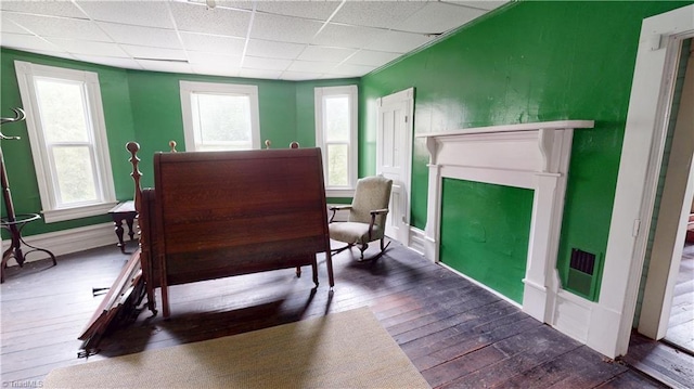 bedroom with hardwood / wood-style flooring, a drop ceiling, a fireplace, and baseboards