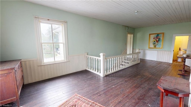 sitting room with a wainscoted wall, wood-type flooring, healthy amount of natural light, and an upstairs landing