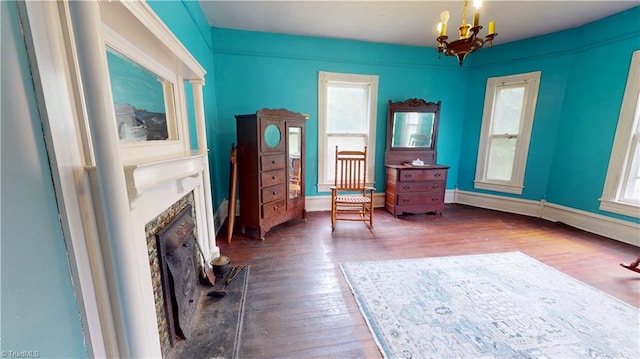 sitting room with a chandelier, a premium fireplace, wood finished floors, and baseboards