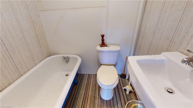 bathroom featuring a sink, toilet, and a soaking tub