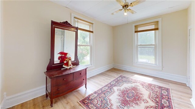 living area with healthy amount of natural light, light wood-style floors, and baseboards