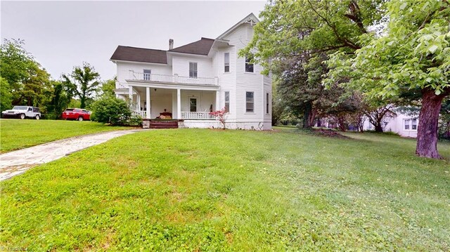 view of front facade featuring covered porch, driveway, a front lawn, and a balcony
