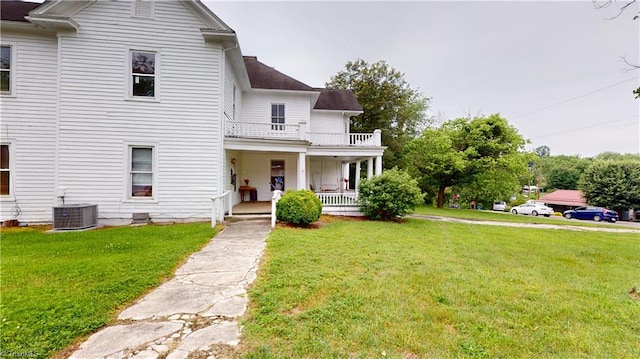 view of front facade with a porch, a balcony, a front yard, and central AC unit