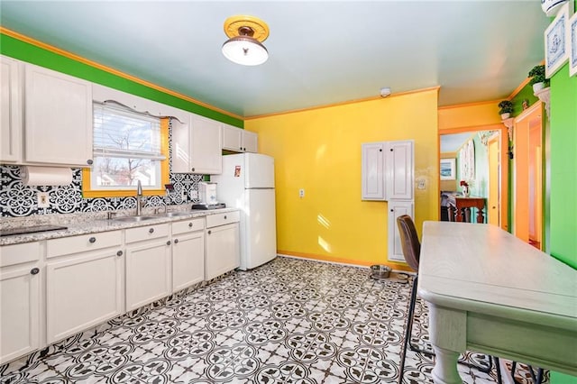 kitchen featuring light stone counters, backsplash, white cabinetry, and white refrigerator