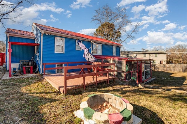 rear view of property with a deck, a yard, and a fire pit