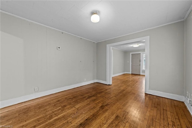 spare room featuring baseboards, hardwood / wood-style floors, and crown molding